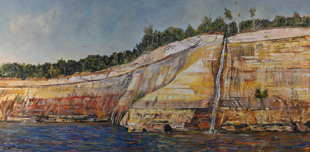 Rugged cliff painting with orange, yellow layers, waterfall, sparse trees, blue water, clear sky.